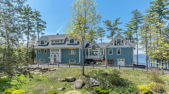 rear view of property featuring a sunroom, a fenced backyard, a garage, and stairs