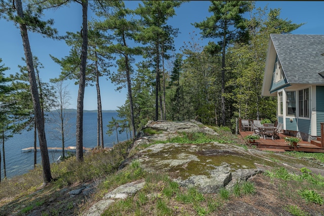 view of yard with a deck with water view and outdoor dining space