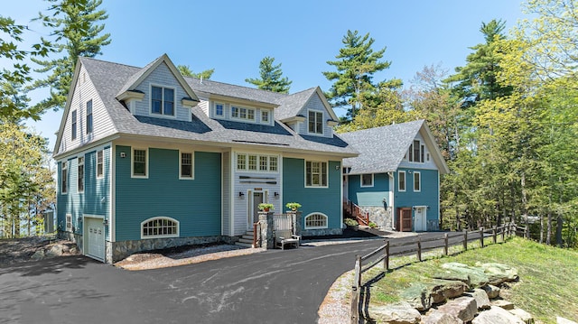 view of front of home featuring driveway, a garage, a shingled roof, and stone siding