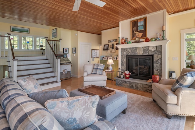 living area featuring wooden ceiling, wood finished floors, stairs, a fireplace, and a ceiling fan