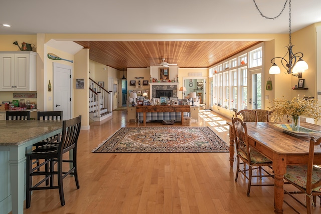 dining room with wood ceiling, stairs, light wood-style flooring, a fireplace, and recessed lighting