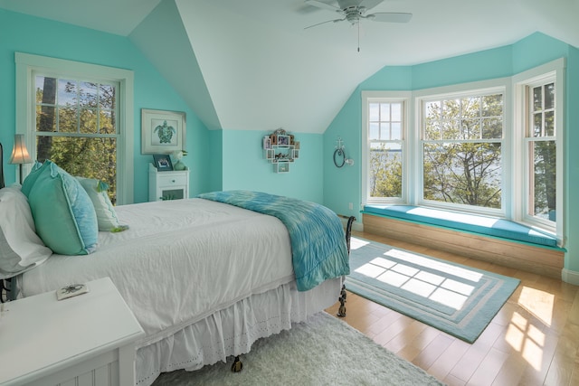 bedroom with multiple windows, vaulted ceiling, wood finished floors, and ceiling fan