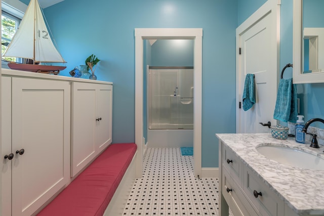 full bath featuring vanity, combined bath / shower with glass door, tile patterned floors, and baseboards