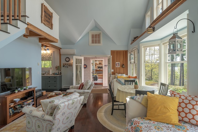 living area with high vaulted ceiling, healthy amount of natural light, and wood finished floors