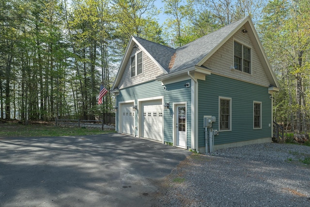 view of home's exterior with driveway and a shingled roof