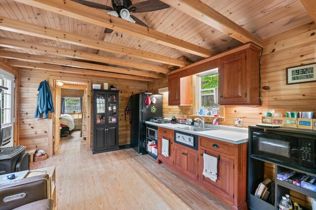 23 Woodland Rd, Winthrop, ME 04364 - kitchen featuring wooden walls, black appliances, a sink, light wood-type flooring, and brown cabinets