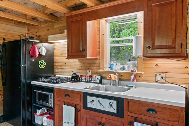 23 Woodland Rd, Winthrop, ME 04364 - kitchen with a sink, wooden walls, freestanding refrigerator, brown cabinets, and beamed ceiling