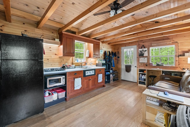 23 Woodland Rd, Winthrop, ME 04364 - kitchen with black appliances, wooden walls, light wood-type flooring, brown cabinetry, and plenty of natural light