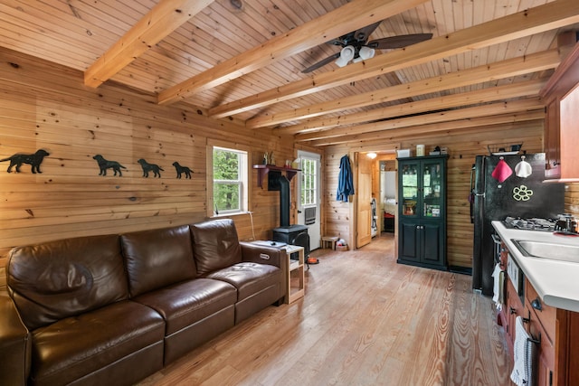 23 Woodland Rd, Winthrop, ME 04364 - living room featuring a wood stove, wood walls, light wood finished floors, beamed ceiling, and wooden ceiling