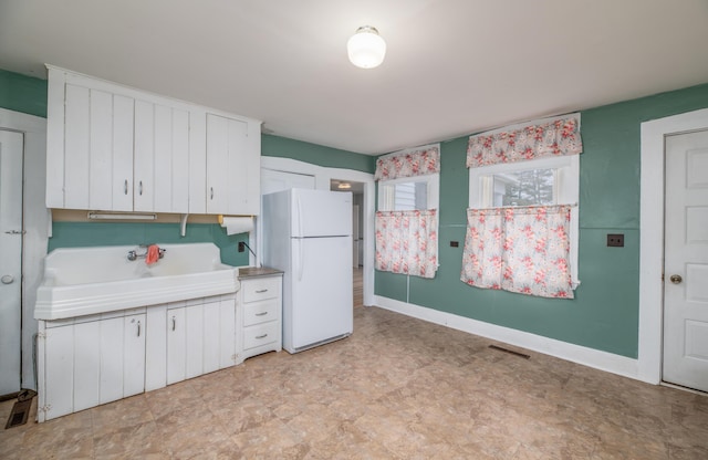 1 High St, Hallowell, ME 04347 - kitchen featuring freestanding refrigerator, white cabinets, light countertops, a sink, and light floors