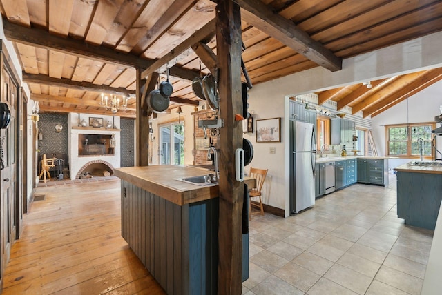 248 Morse Rd, Norway, ME 04268 - kitchen with stainless steel appliances, a sink, wooden ceiling, butcher block counters, and a fireplace