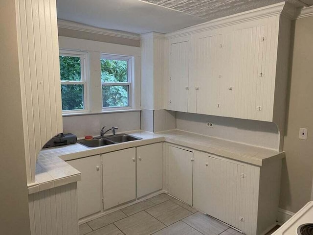 30 Patterson St, Augusta, ME 04330 - kitchen featuring a sink, tile counters, light tile patterned flooring, and white cabinets