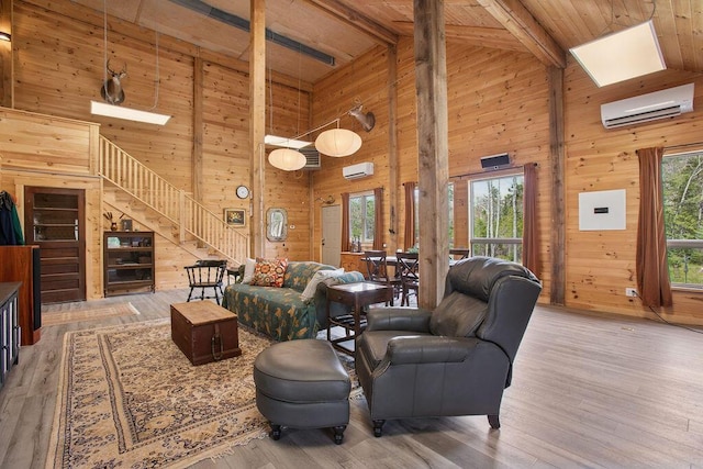 45AND57 Southgate Rd, Kennebunk, ME 04043 - living area with a wall mounted air conditioner, wood walls, high vaulted ceiling, healthy amount of natural light, and stairs