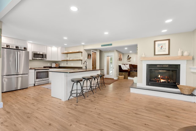10 E Pinnacle Rd Unit 10, Bridgton, ME 04009 - kitchen with stainless steel appliances, dark countertops, a breakfast bar, white cabinetry, and light wood-style floors