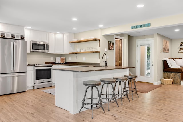 10 E Pinnacle Rd Unit 10, Bridgton, ME 04009 - kitchen with appliances with stainless steel finishes, a sink, dark countertops, light wood-type flooring, and white cabinets