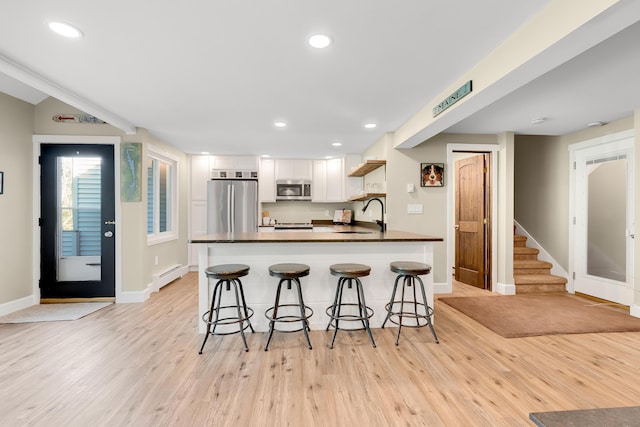 10 E Pinnacle Rd Unit 10, Bridgton, ME 04009 - kitchen with stainless steel appliances, a sink, dark countertops, white cabinets, and baseboard heating