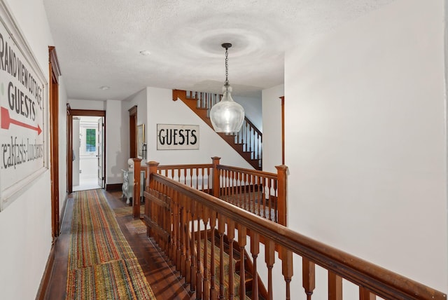 14 Oak St, Kennebunk, ME 04043 - hallway with a textured ceiling, dark wood-style flooring, baseboards, and an upstairs landing