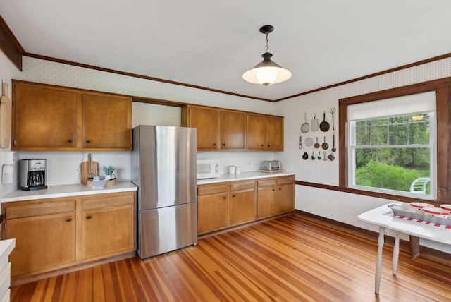 14 Oak St, Kennebunk, ME 04043 - kitchen with wallpapered walls, freestanding refrigerator, white microwave, light wood finished floors, and ornamental molding