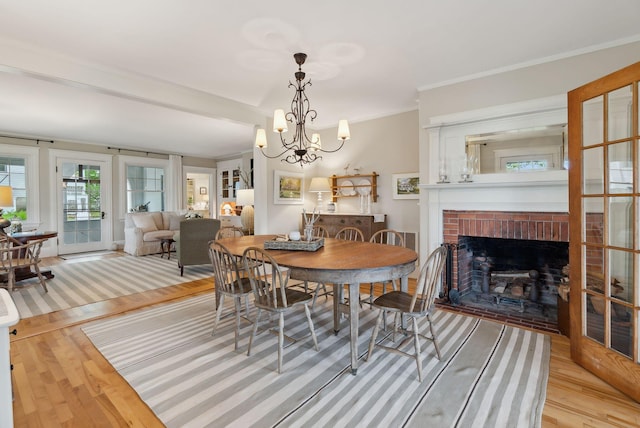 14 Oak St, Kennebunk, ME 04043 - dining area with light wood-style flooring, a fireplace, a chandelier, and ornamental molding