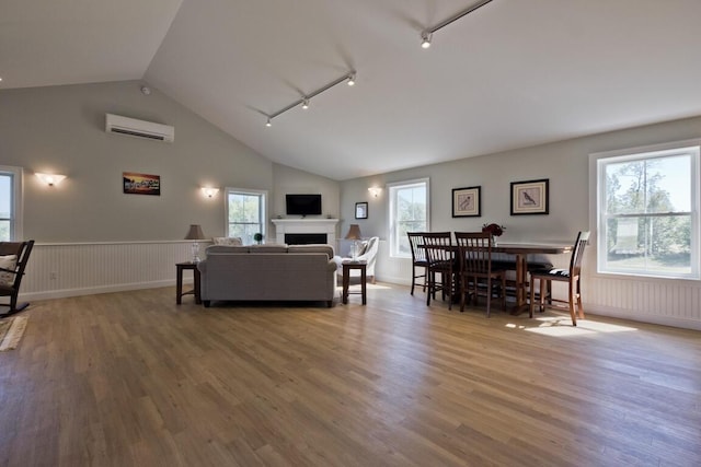 6 D St, Bridgton, ME 04009 - living area with a wall mounted AC, rail lighting, vaulted ceiling, wood finished floors, and healthy amount of natural light