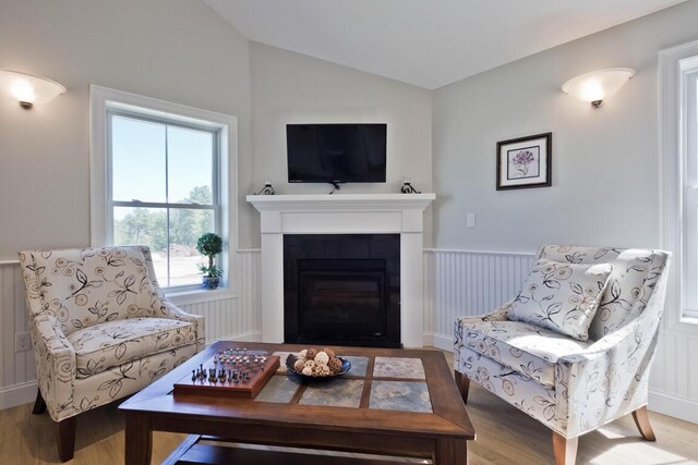 6 D St, Bridgton, ME 04009 - living room with vaulted ceiling, wood finished floors, wainscoting, and a glass covered fireplace