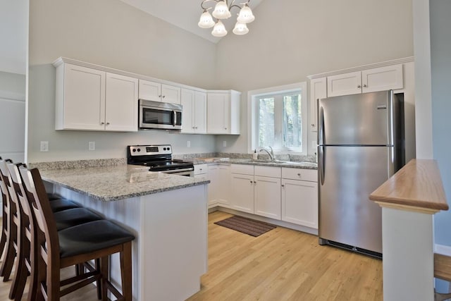 6 D St, Bridgton, ME 04009 - kitchen with appliances with stainless steel finishes, a sink, high vaulted ceiling, a chandelier, and a peninsula