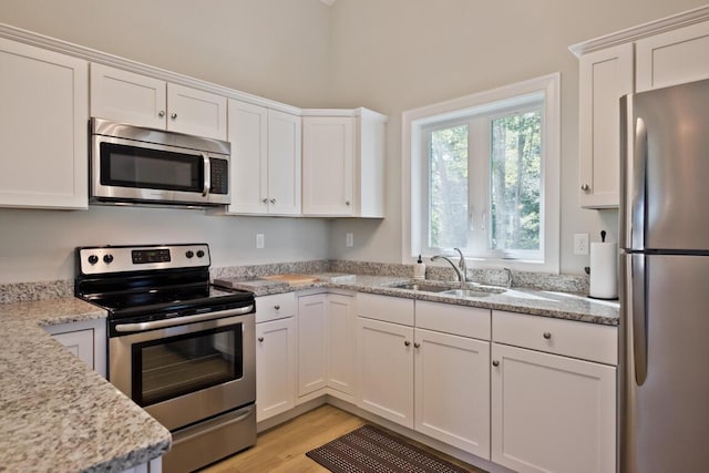 6 D St, Bridgton, ME 04009 - kitchen featuring stainless steel appliances, a sink, white cabinetry, light wood finished floors, and light stone counters