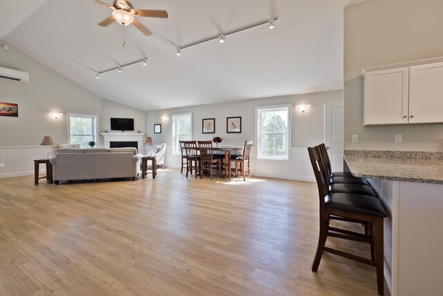 6 D St, Bridgton, ME 04009 - living room featuring rail lighting, ceiling fan, a wall mounted air conditioner, plenty of natural light, and a wainscoted wall