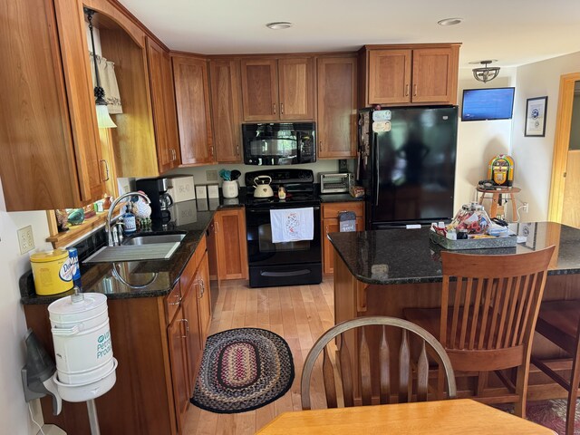 11 Cherry Dr, Embden, ME 04958 - kitchen featuring black appliances, a sink, a breakfast bar area, brown cabinets, and light wood-type flooring