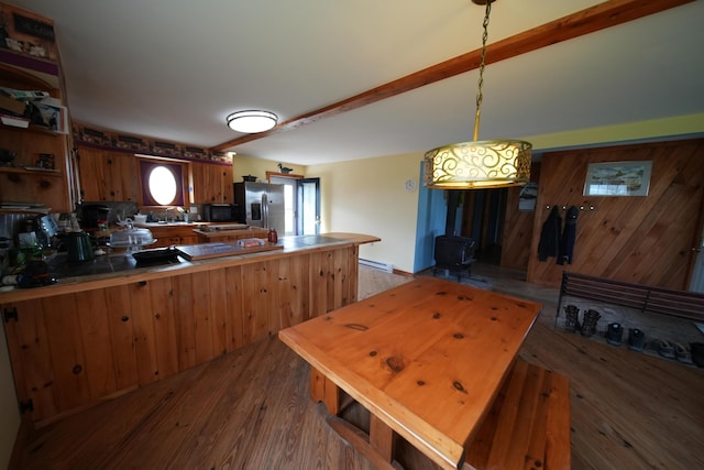 899 Golden Ridge Rd, Sherman, ME 04476 - kitchen with stainless steel fridge, a wood stove, a baseboard heating unit, a peninsula, and beamed ceiling