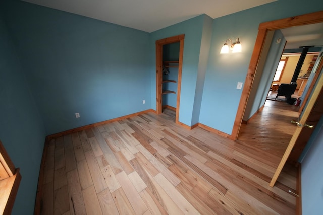 899 Golden Ridge Rd, Sherman, ME 04476 - unfurnished bedroom with wood finished floors, a wood stove, and baseboards