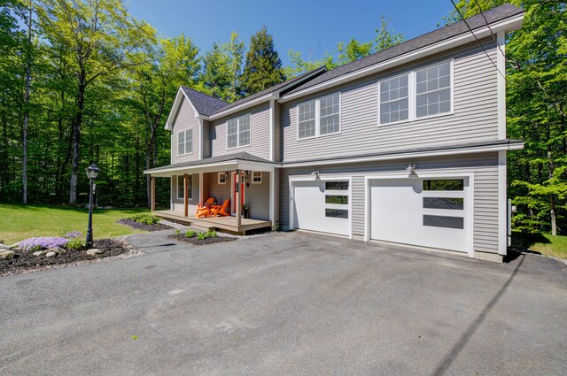 26 John Adams Ct, Naples, ME 04055 - view of front of home featuring covered porch, asphalt driveway, a garage, and a front lawn