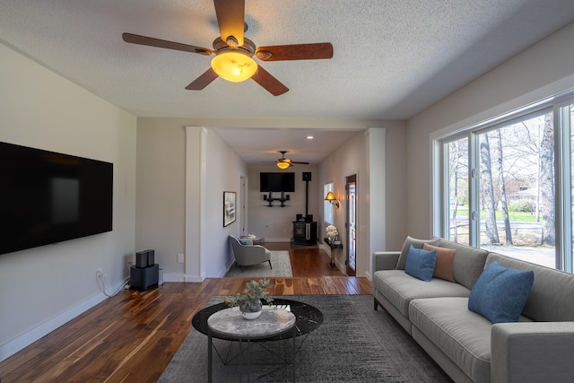 46 Silver Rdg, Veazie, ME 04401 - living room with a wood stove, wood finished floors, a ceiling fan, baseboards, and a textured ceiling