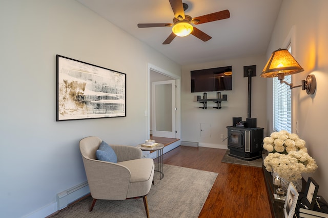 46 Silver Rdg, Veazie, ME 04401 - living area with a ceiling fan, a wood stove, wood finished floors, baseboard heating, and baseboards