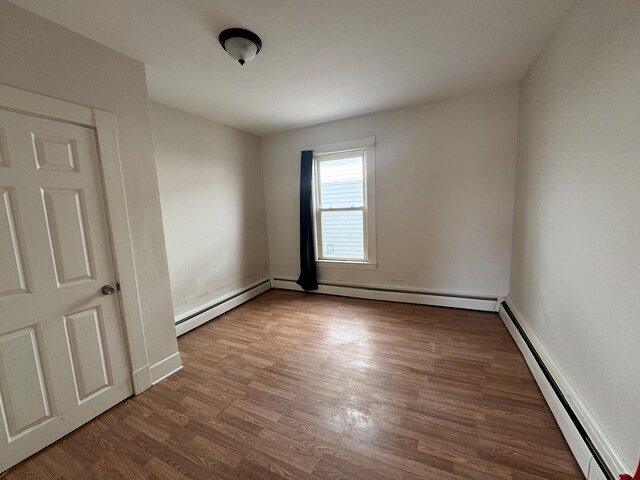 932 Lisbon St, Lewiston, ME 04240 - empty room with a baseboard radiator, wood finished floors, and baseboards