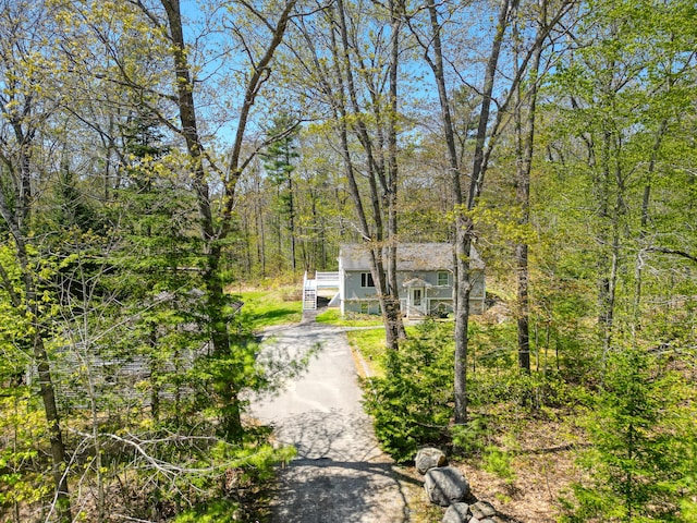 15 Northwood Ct, Wiscasset, ME 04578 - view of front of house with stairway, driveway, and a forest view