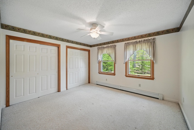 15 Northwood Ct, Wiscasset, ME 04578 - unfurnished bedroom with a baseboard radiator, multiple closets, light carpet, baseboards, and a textured ceiling
