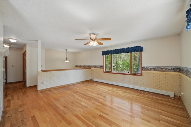 15 Northwood Ct, Wiscasset, ME 04578 - spare room featuring wallpapered walls, baseboard heating, light wood-type flooring, a wainscoted wall, and baseboards