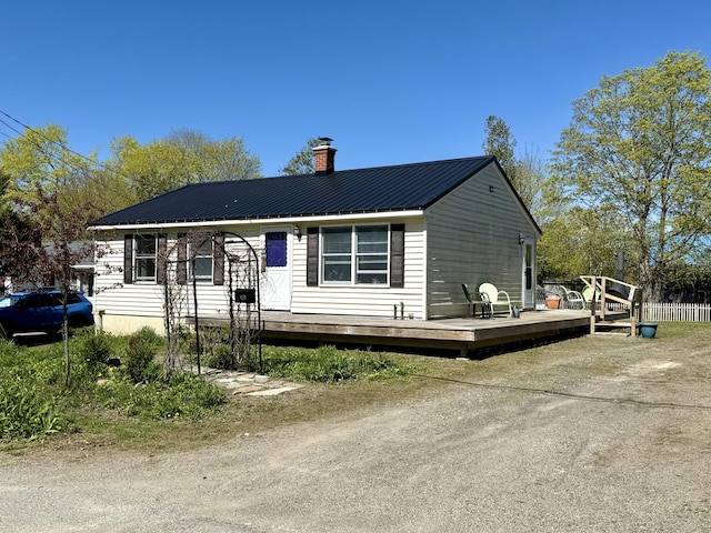 view of front of house featuring a chimney, a wooden deck, and metal roof