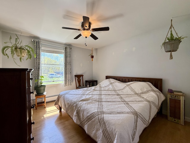 bedroom with a baseboard radiator, wood finished floors, and a ceiling fan