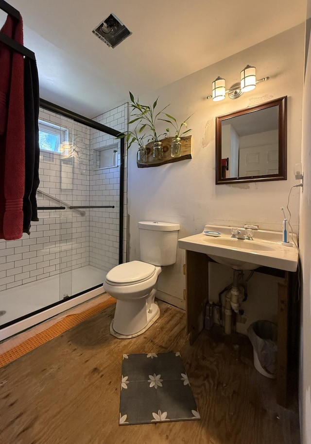bathroom featuring wood finished floors, a stall shower, and toilet