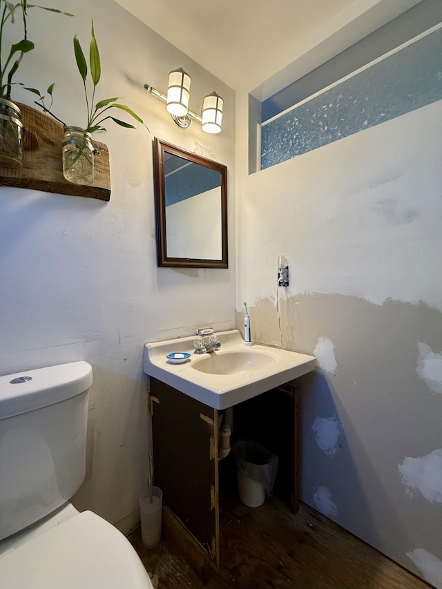 half bathroom with toilet, wood finished floors, and vanity