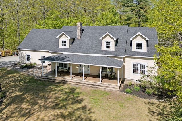 76 Asbury Ln, Acton, ME 04001 - view of front of house featuring a chimney, covered porch, a front lawn, and roof with shingles