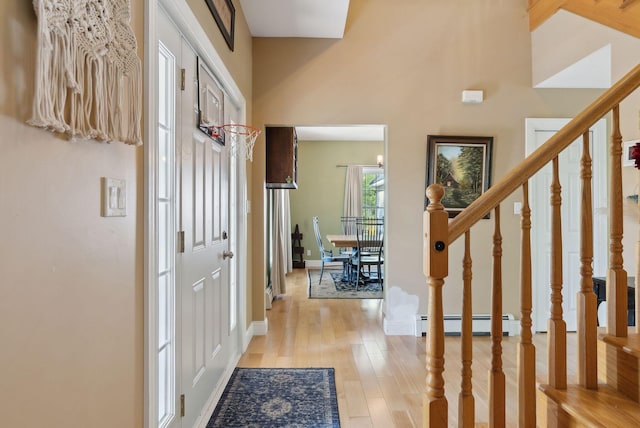 76 Asbury Ln, Acton, ME 04001 - foyer featuring baseboard heating, light wood finished floors, stairs, baseboards, and a towering ceiling