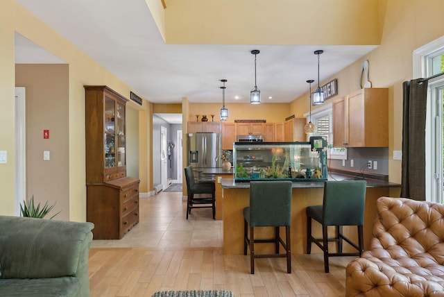 76 Asbury Ln, Acton, ME 04001 - kitchen with open floor plan, a peninsula, stainless steel fridge with ice dispenser, a breakfast bar area, and dark countertops