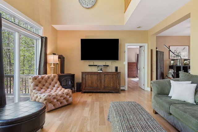 76 Asbury Ln, Acton, ME 04001 - living area with a wood stove, light wood-style floors, and a baseboard heating unit