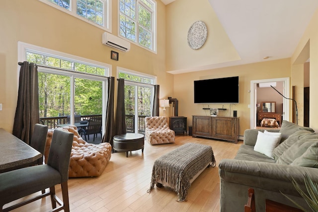76 Asbury Ln, Acton, ME 04001 - living area with a wall mounted AC, a wood stove, a towering ceiling, and light wood finished floors