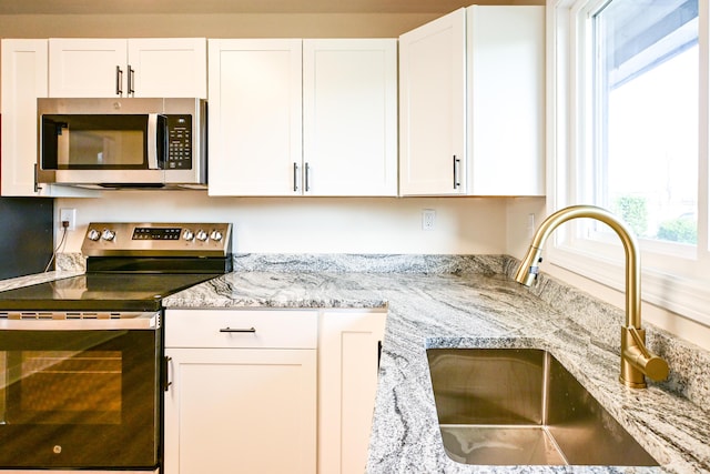 57 Mountfort St, Portland, ME 04101 - kitchen featuring appliances with stainless steel finishes, a sink, white cabinets, and light stone countertops