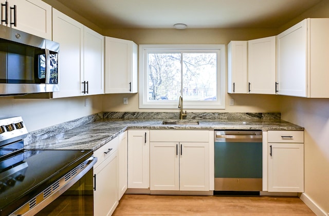 57 Mountfort St, Portland, ME 04101 - kitchen with stainless steel appliances, a sink, light wood-style floors, and white cabinetry