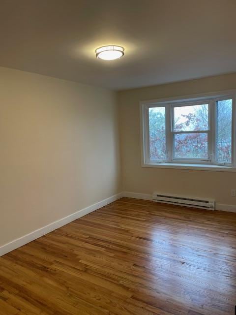 57 Mountfort St, Portland, ME 04101 - empty room featuring a baseboard heating unit, baseboards, and wood finished floors